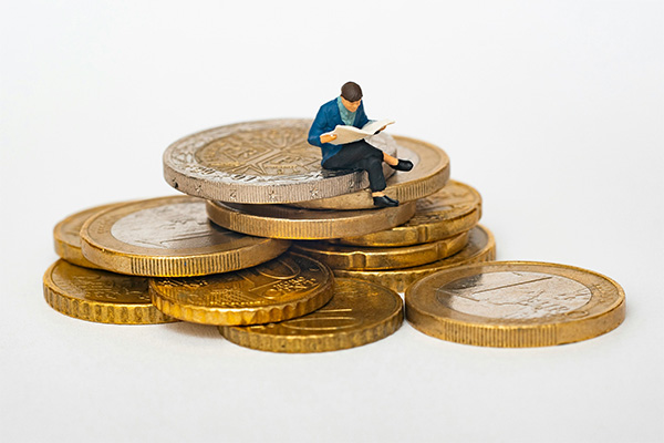 L'image d'une personne assise sur des immenses pièces de monnaie.